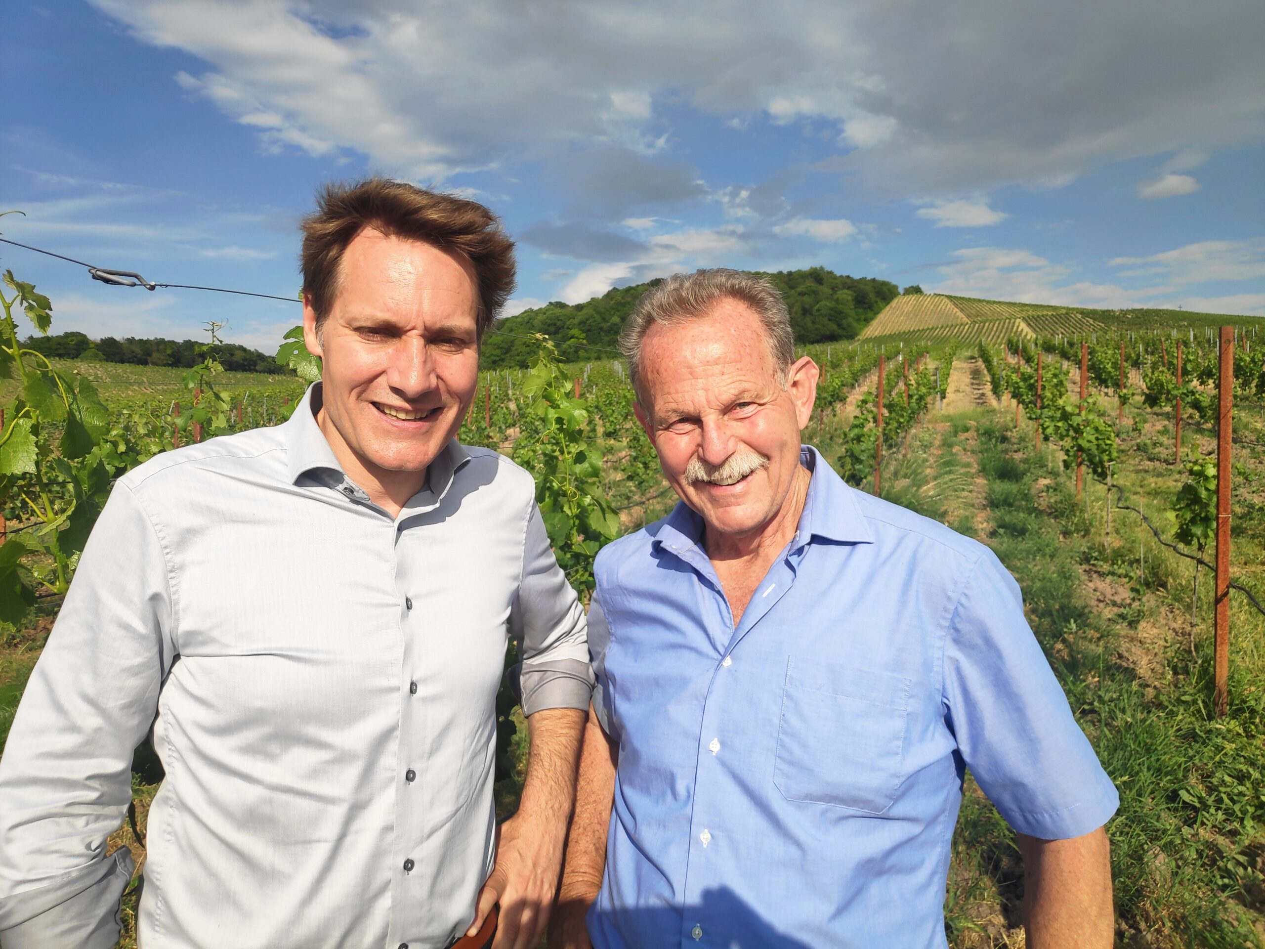 Der Fraktionschef der Grünen im Landtag Ludwig Hartmann und Paul Knoblach beim Besuch des Bioweinguts von Sabrina Bausewein und Matthias Popp. Zu sehen sind im Hintergrund Pfähle aus Cortenstahl ohne Verzinkung. Angebaut wird die Rebsorte Blanc de Noir, eine pilzwiderstandsfähige Weißweinrebe.