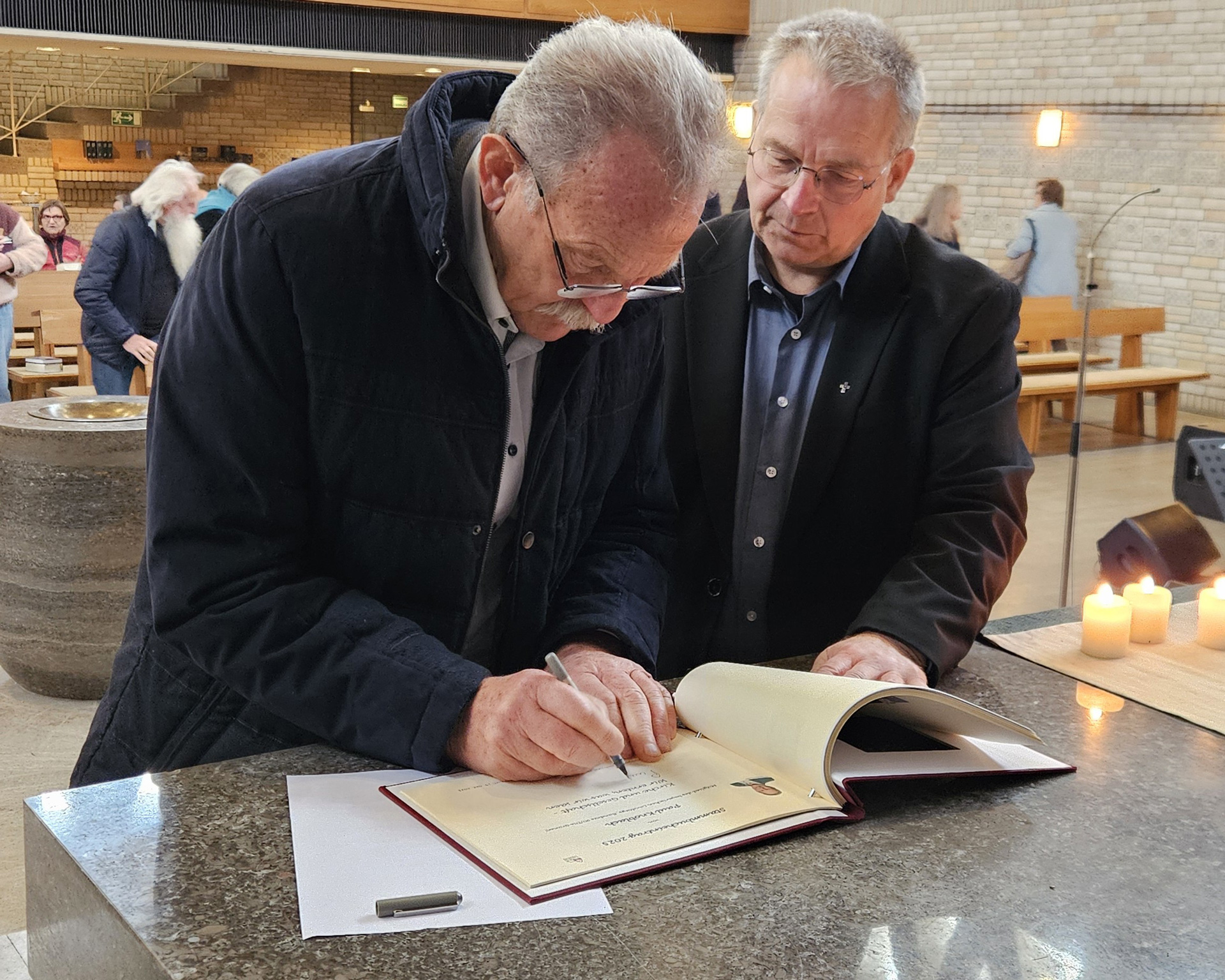 Paul Knoblach trägt sich mit Unterstützung von Pfarrer Wolfgang Weich in das Stammbuch der evangelischen Christuskirche ein. Foto: Gert Ehrlich